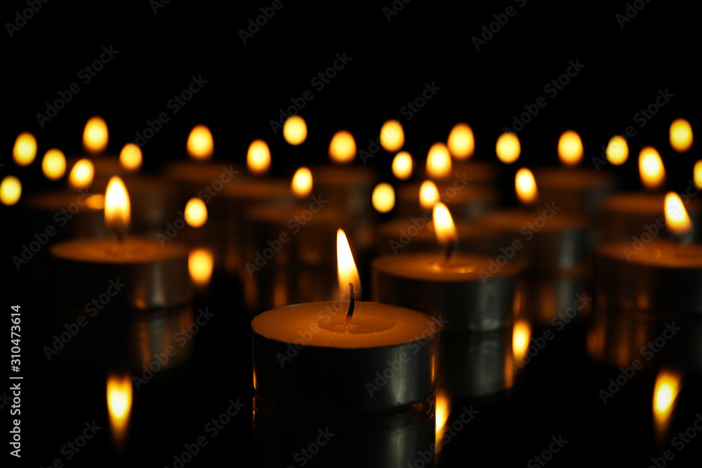 Group of burning candles on black background, close up
