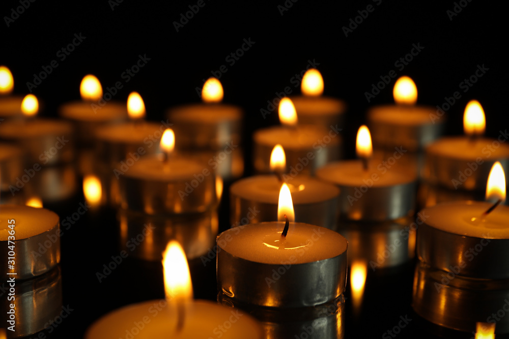 Group of burning candles on black background, close up Group of burning candles on black background, close up