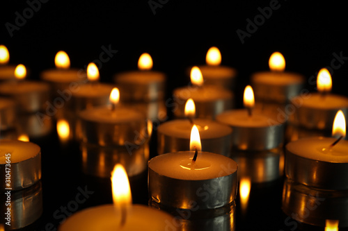 Group of burning candles on black background, close up