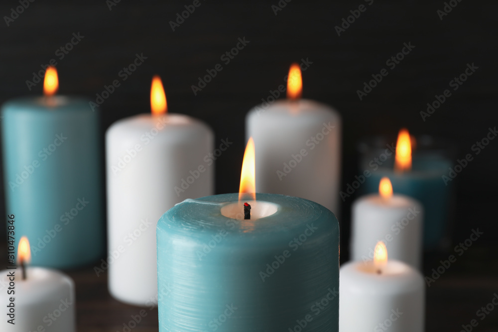 Burning candles on dark wooden background, close up