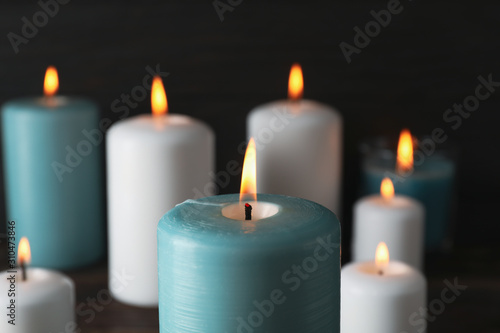 Burning candles on dark wooden background  close up