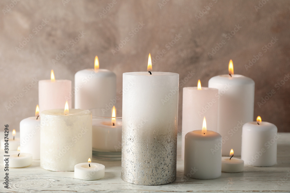 Different burning candles against brown background, close up Different burning candles against brown background, close up