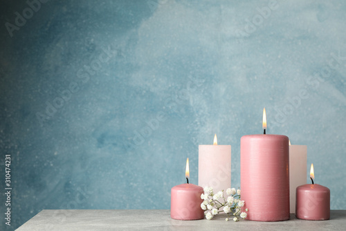 Burning candles and flower against blue background, space for text