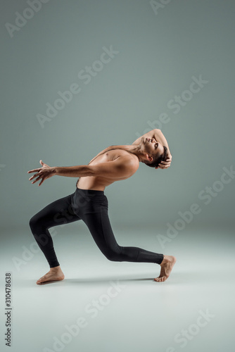side view of handsome dancer with closed eyes in black leggings dancing contemporary on dark background