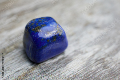 close up of blue gemstone lapis lazuli on wooden background with copy space