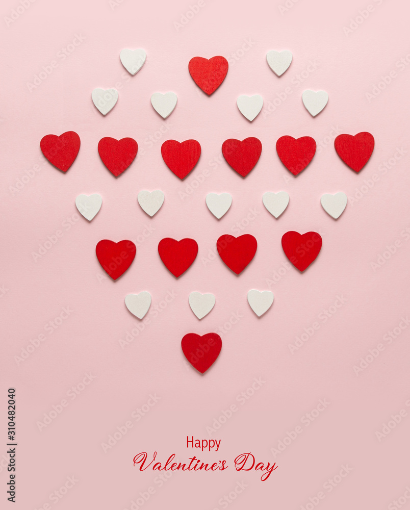 Red wooden hearts on the pastel pink background. Abstract background with wooden cut shapes. Valentine, greeting cards, invitation