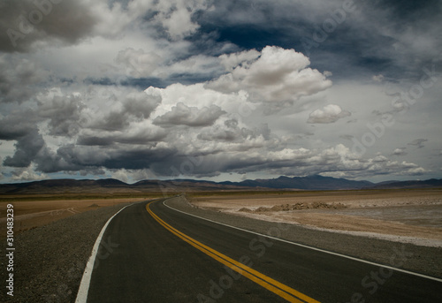 Pov. Empty asphalt highway in the desert under a dramatic cloudy sky in the Andes mountain range
