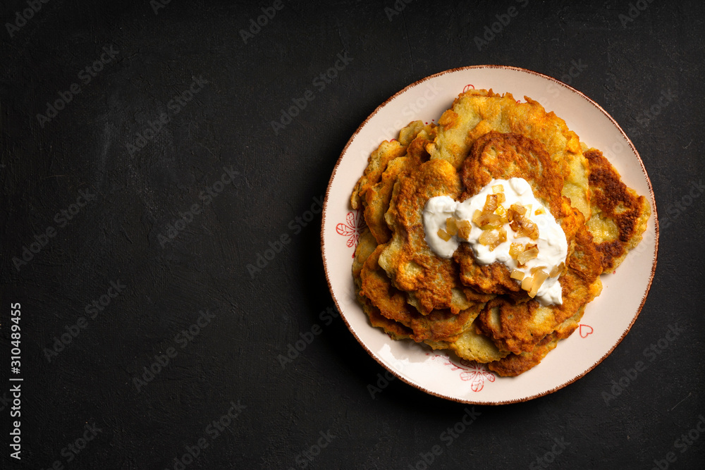 Exposition of home made potato pancakes on black table, traditional tasty food.
