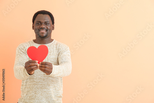 African-American man with red heart on color background © Pixel-Shot