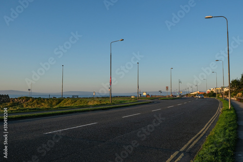 Sunlit road along the Wild Atlantic Way, going along Salthill promenade near Galway, in ireland. Tekan at sunrise on a sunny day.