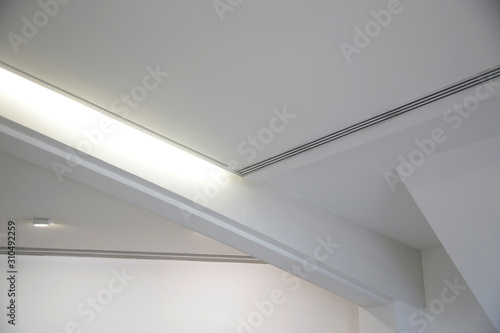 Girder between ceiling and wall. Abstract architecture fragment. Modern office building interior with polygonal white concrete elements. Diagonal geometric composition in light gray halftones.