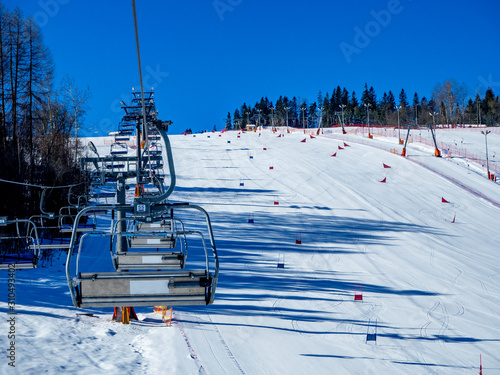 Ski lifts (chairlift and ski tow), and ski slope with slalom gates for skiers and snowboarders in Bialka ski resort in Poland photo