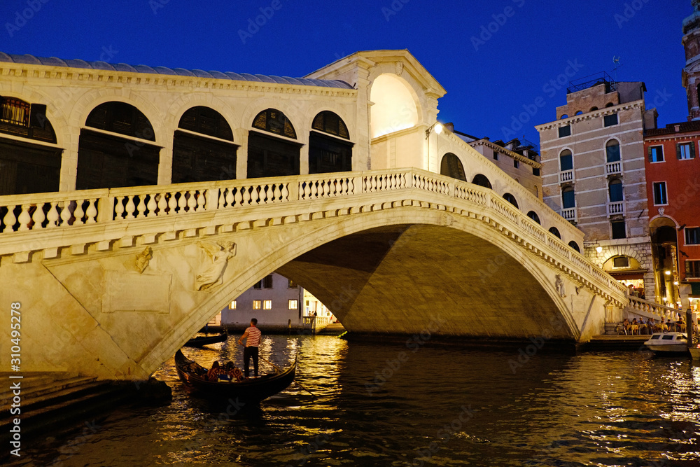 Grand Canal and Rialto bridge, Venice, Italy. Beautiful romantic city lights in Italy. Beautiful view of traditional gondola on famous Rialto Bridge at night. Vacation in Italian city on water. 