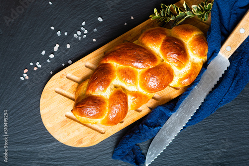 Homemade food concept fresh baked bread braid challah or brioche on black slate stone with copy space photo