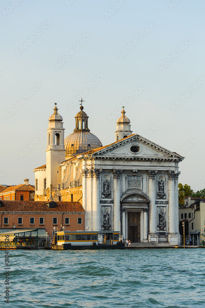 Gold sunset in Grand Canal, Venice, Italy. Bright sunny panorama view of Grand Canal with old buildings and church. Beautiful photo background of the venetian canal in the morning.