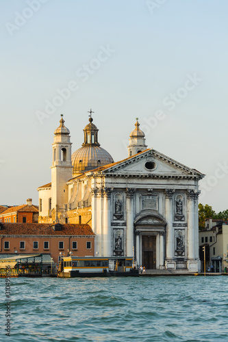 Gold sunset in Grand Canal, Venice, Italy. Bright sunny panorama view of Grand Canal with old buildings and church. Beautiful photo background of the venetian canal in the morning.