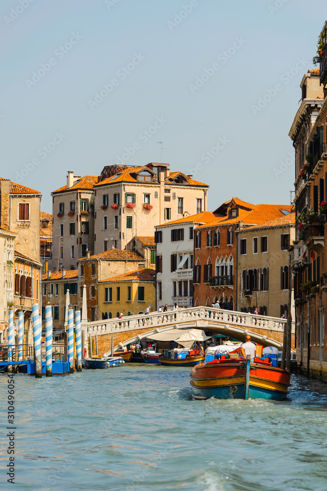 Landscape of the venetian canal with gondola across the canal. Historic houses of the Grand Canal in Venice, Italy. Traditional Canal in Venice with bridge.