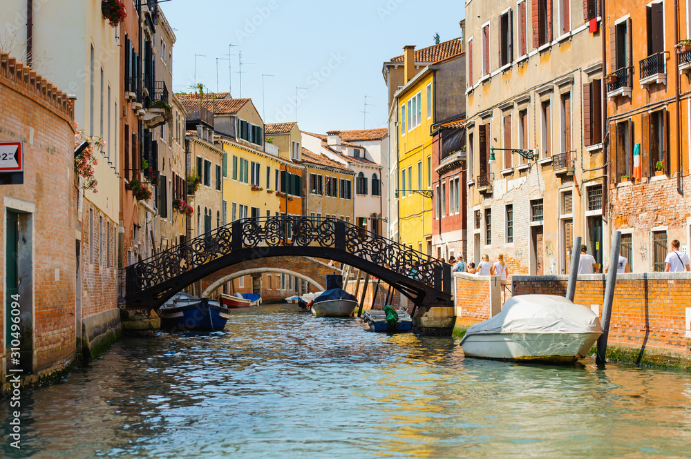 Landscape of the venetian canal with gondola across the canal. Historic houses of the Grand Canal in Venice, Italy. Traditional Canal in Venice with bridge.