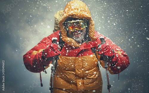 Fotografia, Obraz Climber reaching the summit. Snow storm.