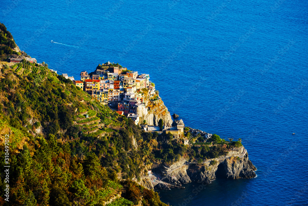Colorful traditional houses on a rock over Mediterranean sea on sunset, Manarola, Cinque Terre, Liguria, Italy. Colors of amazing little Italian village on mountain. Quiet sky and peaceful sea.
