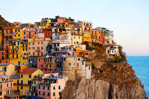 Colorful traditional houses on a rock over Mediterranean sea on sunset, Manarola, Cinque Terre, Liguria, Italy. Colors of amazing little Italian village on mountain. Quiet sky and peaceful sea.