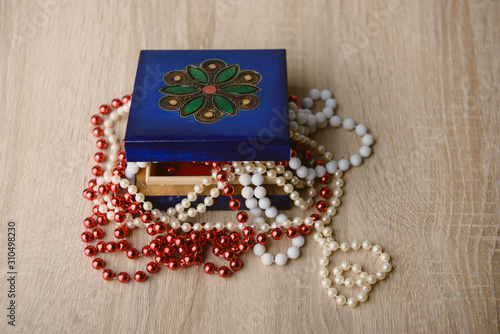 Gift box and red beads necklace on wooden background