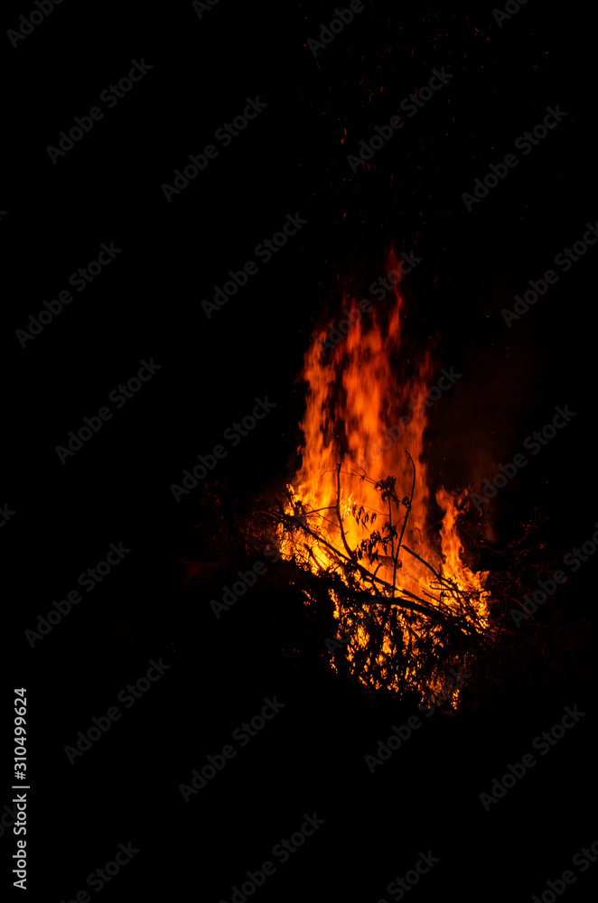 Bonfire burning trees at night. Large orange flame isolated on a black background. Fire on black. Brightly, heat, light, camping, big bonfire Bonfire burning trees at night. Large orange flame isolated on a black background. Fire on black. Brightly, heat, light, camping, big bonfire