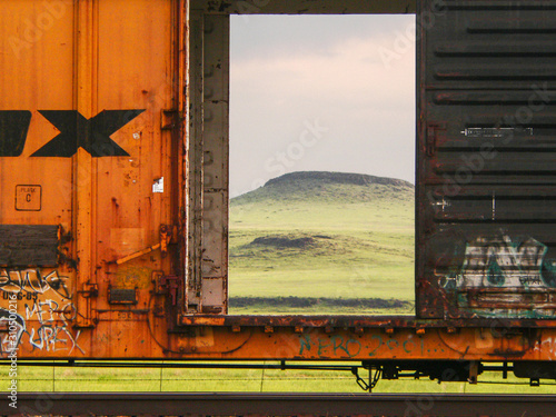 Railroad boxcar with opened door and early morning vista in the background photo