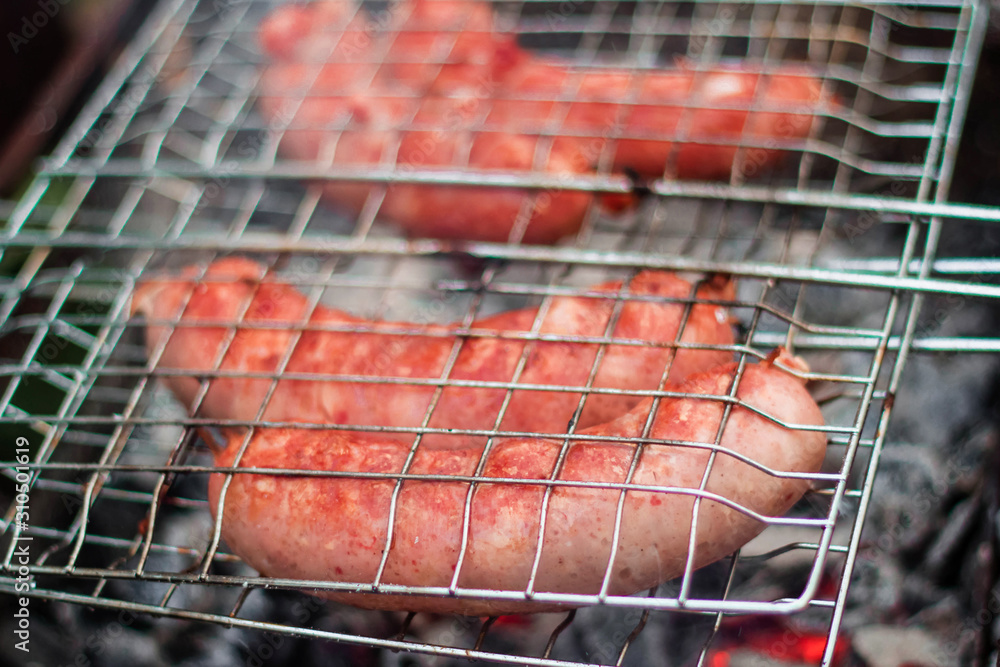 Sausages on the grill are grilled on the coals in the open air.