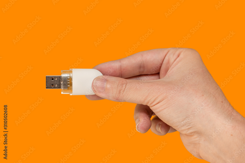 White USB Flash drive on hand with isolated orange background White USB Flash drive on hand with isolated orange background