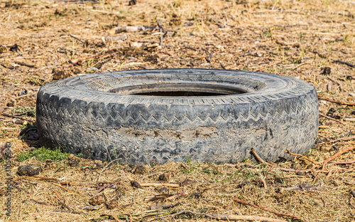 Old truck tire on dry grass background