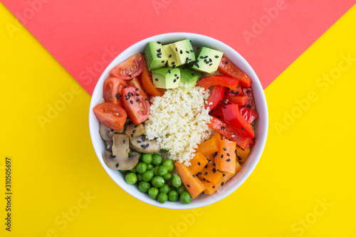 Vegan poke bowl with couscous  and vegetables in the white bowl in the center of the bicolor background. Top view. Copy space. Closeup. photo