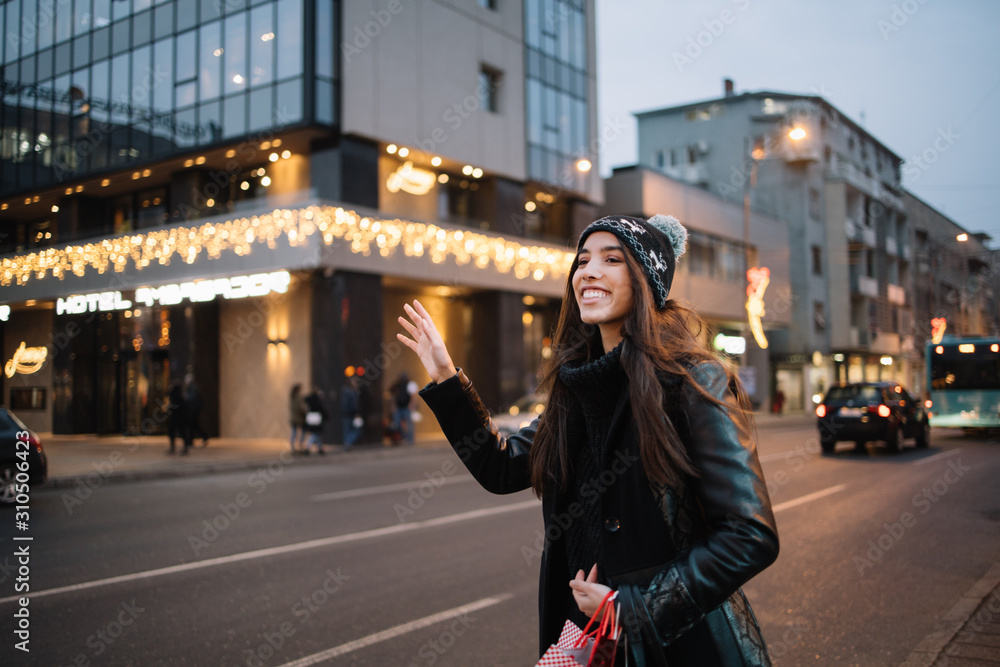 Smiling girl with hat waving for taxi