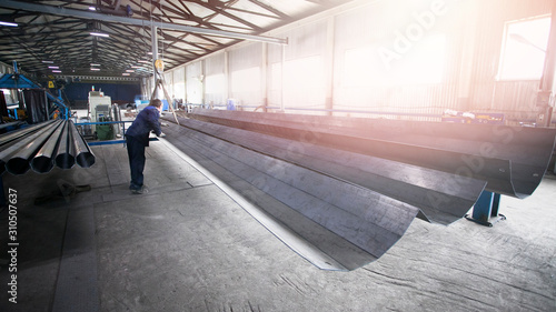 Professional worker at the plant moving metal products. Production of faceted metal pillars