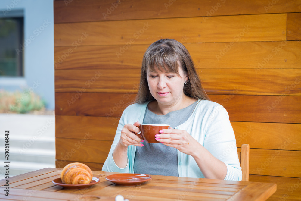 Young Caucasian woman with straight hair drinking tea in a coffee shop Young Caucasian woman with straight hair drinking tea in a coffee shop