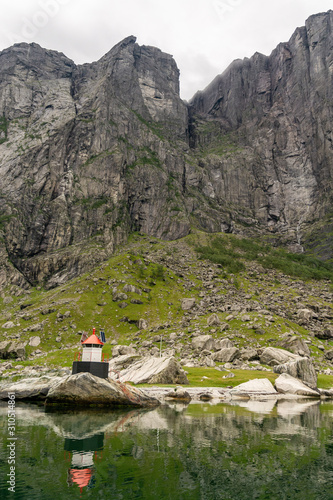 Small idyllic lighthouse surrounded by mountains in the majestic Lysefjord in Norway. Seen from the seaside