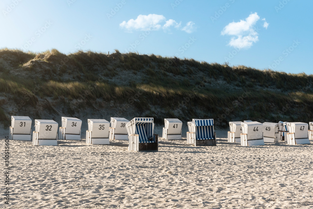Naklejka premium North Sea beach with wicker chairs and grass dunes on Sylt island