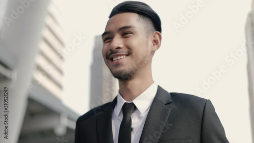 Wallpaper Mural Handsome asian businessman in a black suit smiling while standing outside on the street near a big office building urban. Torontodigital.ca