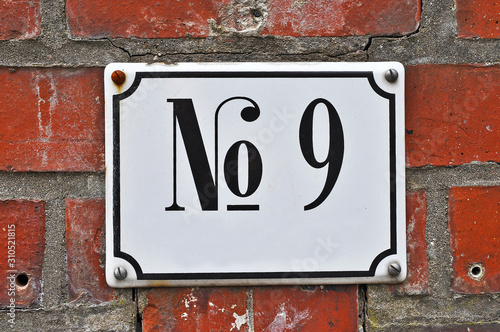 A house number plaque, showing the number nine (9)