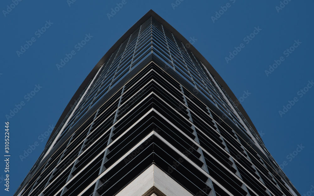 View of the skyscraper from below against a blue sky. Close-up View of the skyscraper from below against a blue sky. Close-up