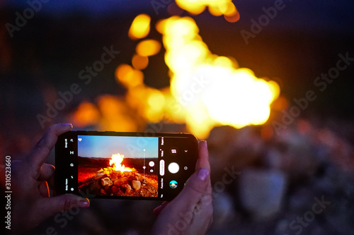 Girl shooting a photo to the fire with smartphone photo