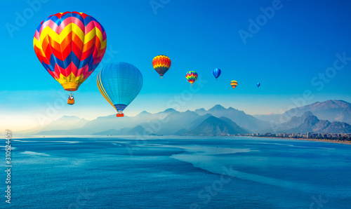 Fototapeta Naklejka Na Ścianę i Meble -  Silhouetted people relaxing in Antalya harbor over sunset sky and high mountains