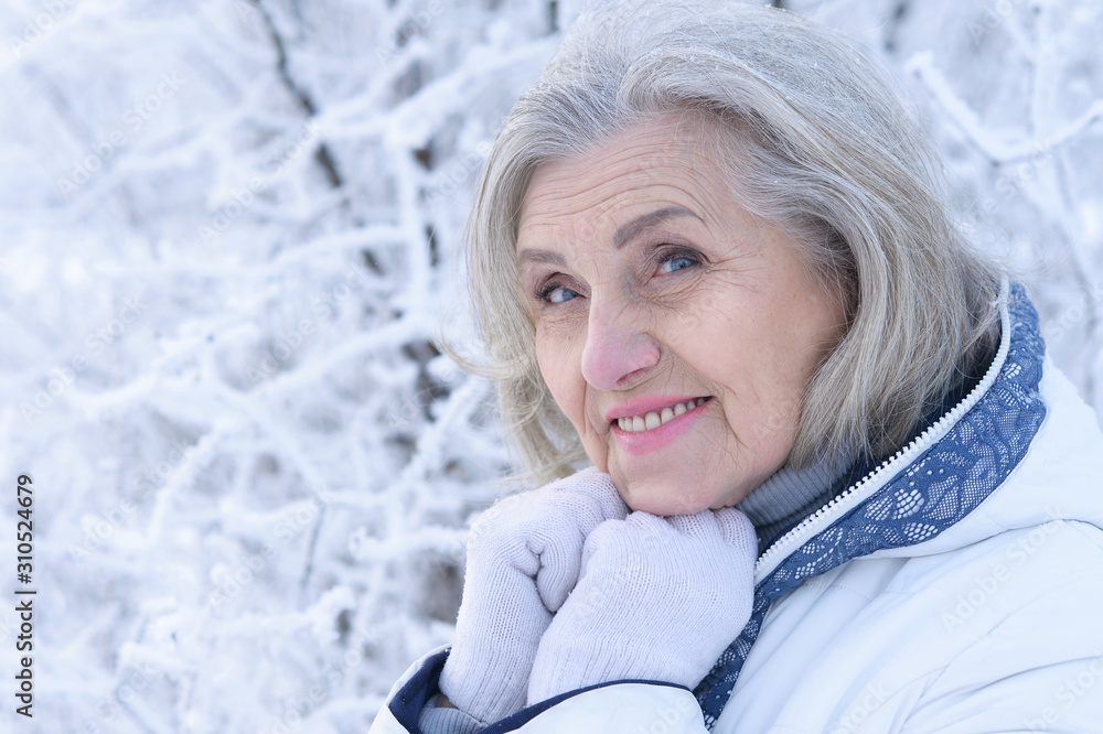 Portrait of happy beautiful senior woman posing in snowy winter park Portrait of happy beautiful senior woman posing in snowy winter park