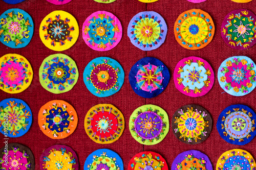 Small round embroidery  full of colors  shown on a red background