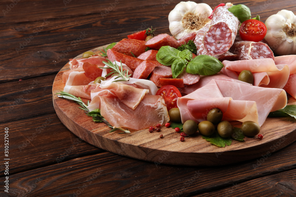 Food tray with delicious salami, pieces of sliced prosciutto crudo, sausage and basil. Meat platter Food tray with delicious salami, pieces of sliced prosciutto crudo, sausage and basil. Meat platter
