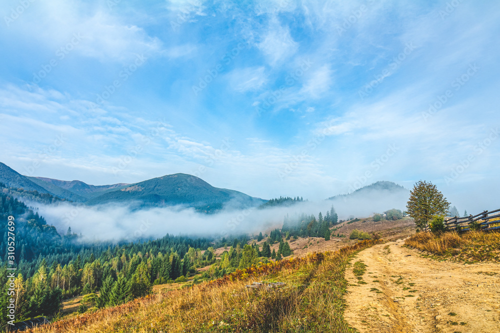 Aerial view amazing over of the Carpathian Mountains or Carpathians with Beautiful autumn landscape , sunrise, blue sky with white clouds, fog between the mountain slopes