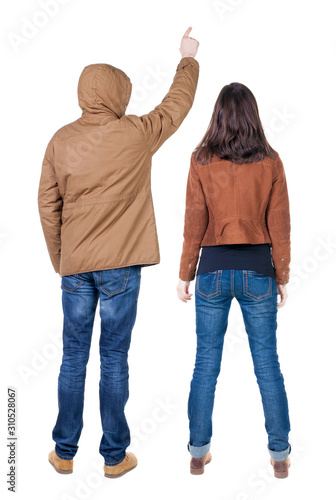 Back view of couple couple in winter jackets pointing.