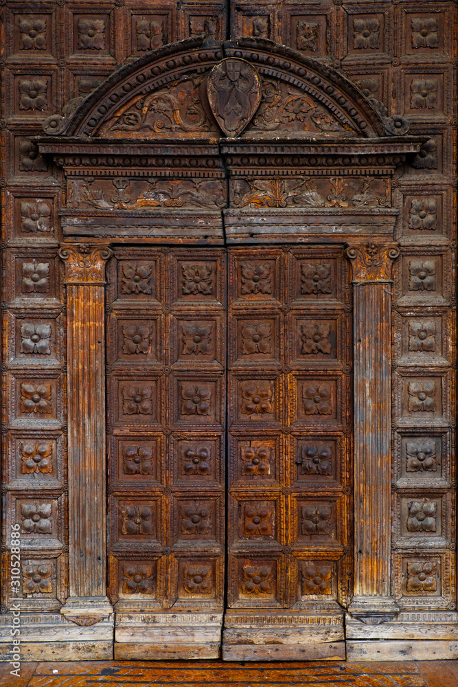 Old wooden textured front door to Italian, European house. Facade of antique home in Italy, entrance city door in Europe. Old wooden textured front door to Italian, European house. Facade of antique home in Italy, entrance city door in Europe.