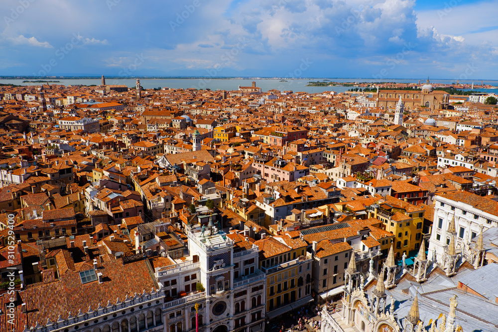 Aerial view of famous San Marco square with many people Venice, Italy. Top view of Venice piazza from the Campanile tower and Doges' Palace. Cityscape panorama of Italian houses with red roofs.