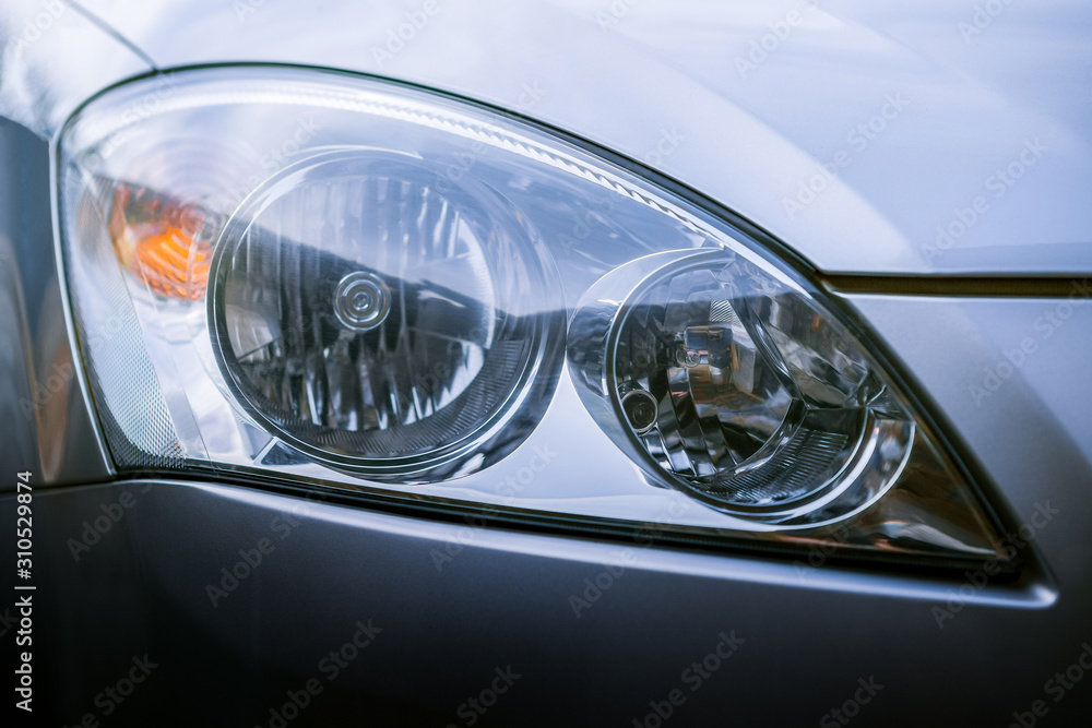 Headlights of the silver car close up with yellow turn signal. Clean glass after washing and wiping. The front of the car. Close-up exterior of the car xenon lamp.